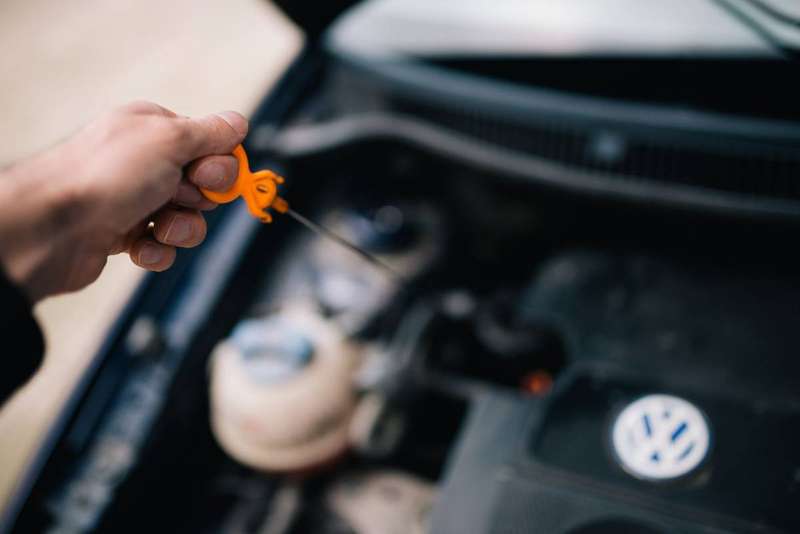 Close-up of a mechanic pulling the dipstick to check oil