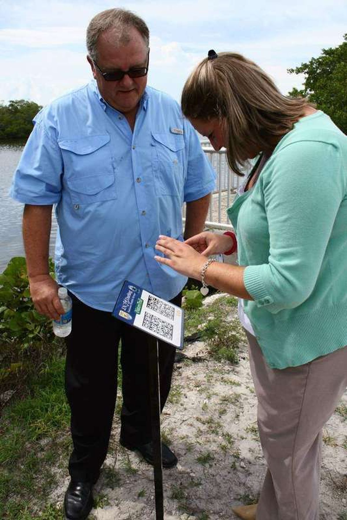 A person holding a smartphone up to scan a QR code displayed on a sign