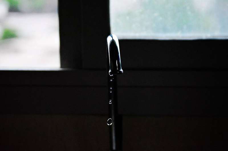 A tap photographed against a window, a reminder that even a small steady drip adds up fast