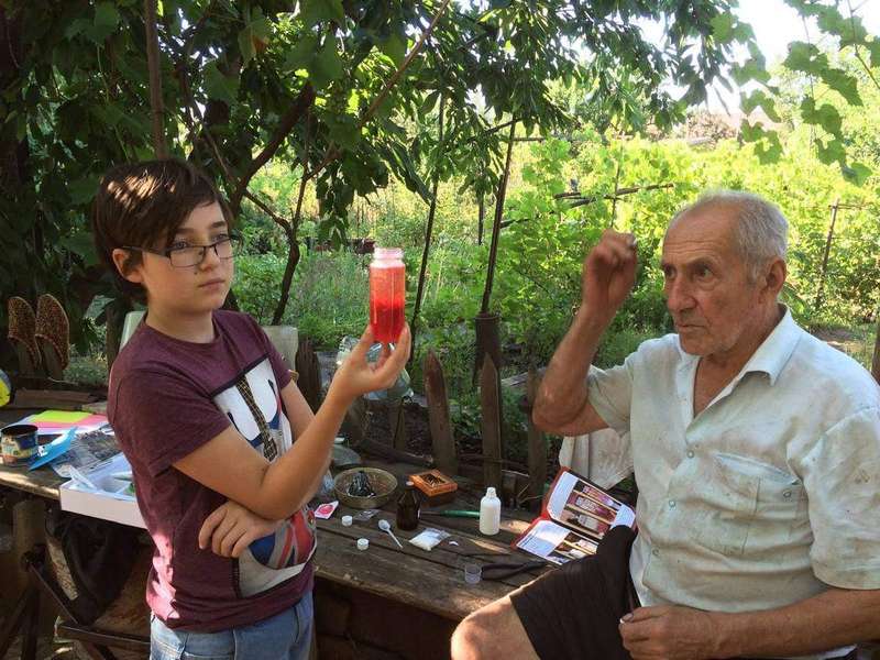 A boy and his grandfather watch a baking soda and vinegar volcano erupt, the same acid-base reaction that leavens batters.