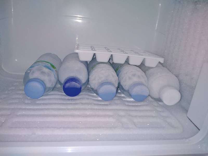 Water bottles and an ice cube tray inside a home freezer