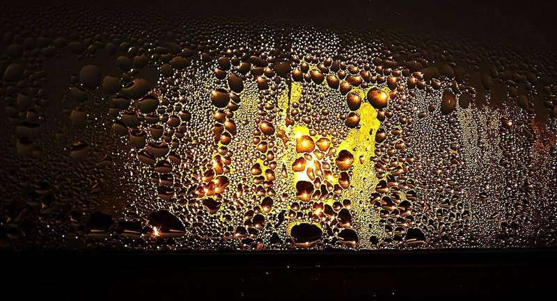 Condensation droplets on a window glowing in low light