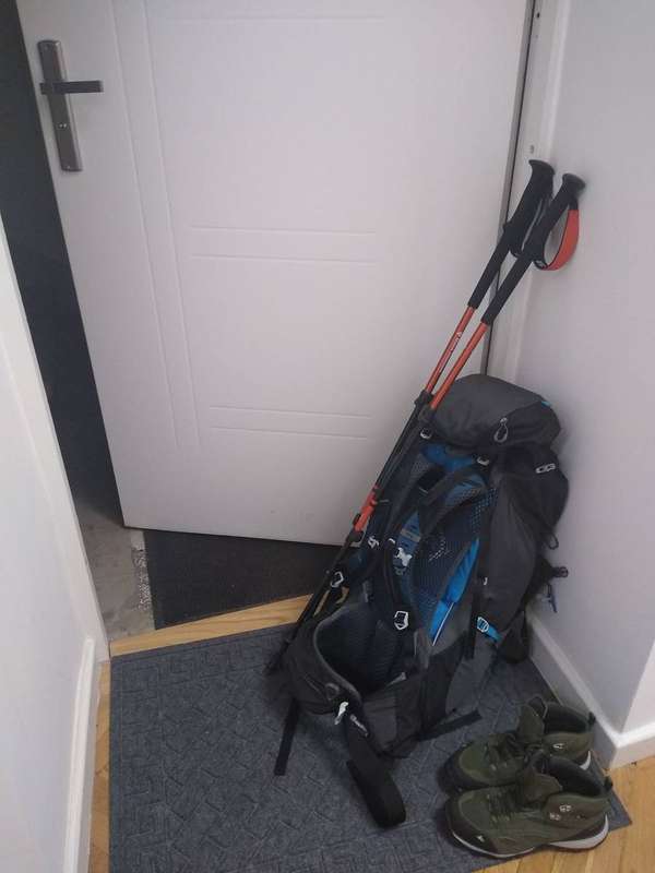 A packed hiking backpack with trekking poles attached, ready for the trail