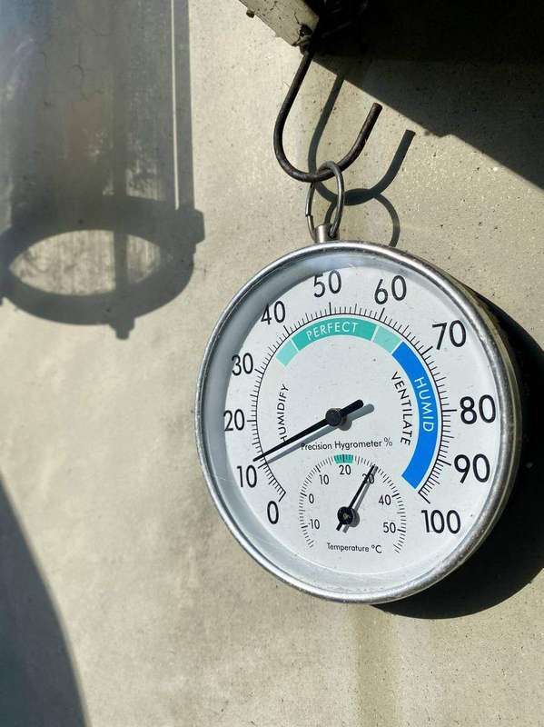 A hygrometer held in a hand displays the room's relative humidity