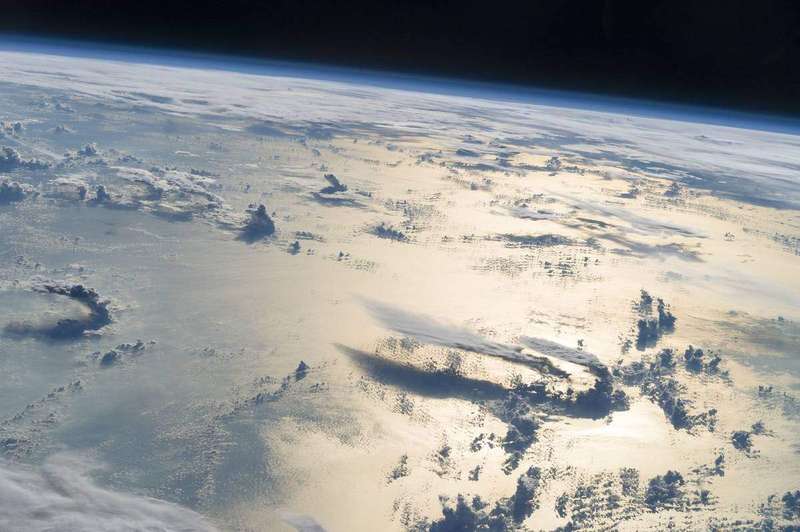 Earth photographed from orbit, its thin atmosphere glowing against the black of space