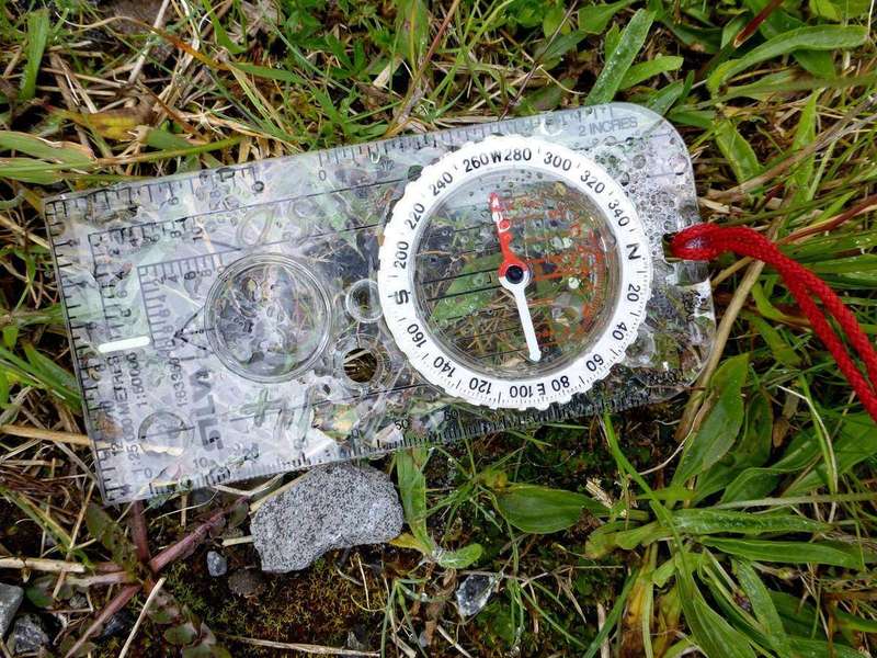 A hiker's compass lying on the ground
