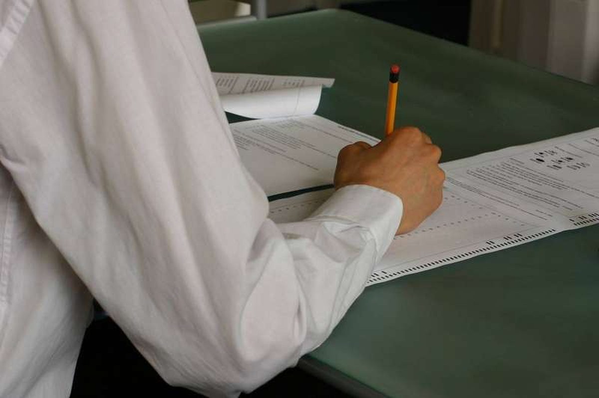 A student's hand writing during an exam
