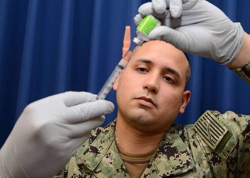 A Navy medical specialist preparing a syringe with influenza vaccine before administering flu shots