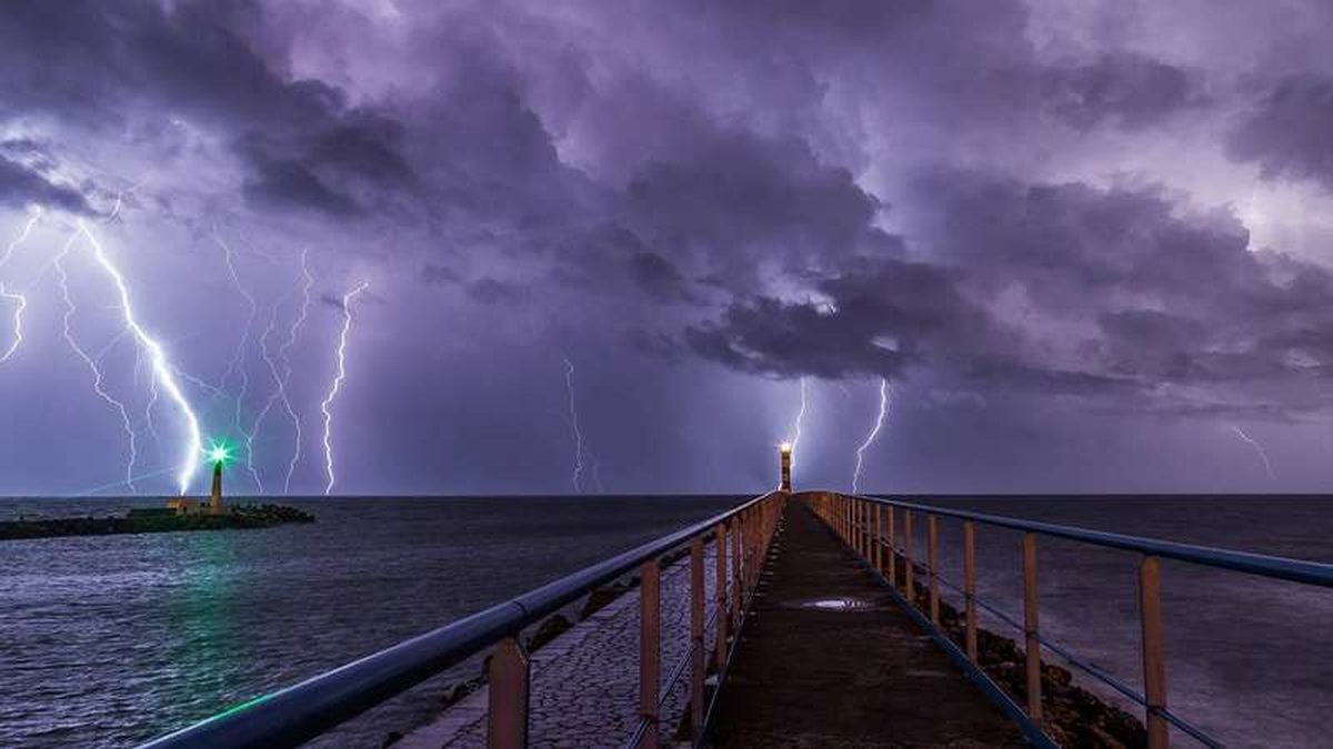 A lighthouse in an overnight storm with lightning, a dramatic weather event