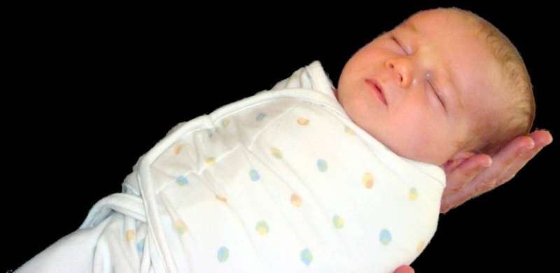 A three-week-old infant wrapped in a swaddle