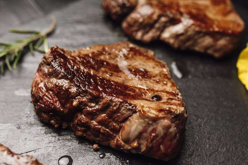 A grilled steak plated with herbs, ready for serving
