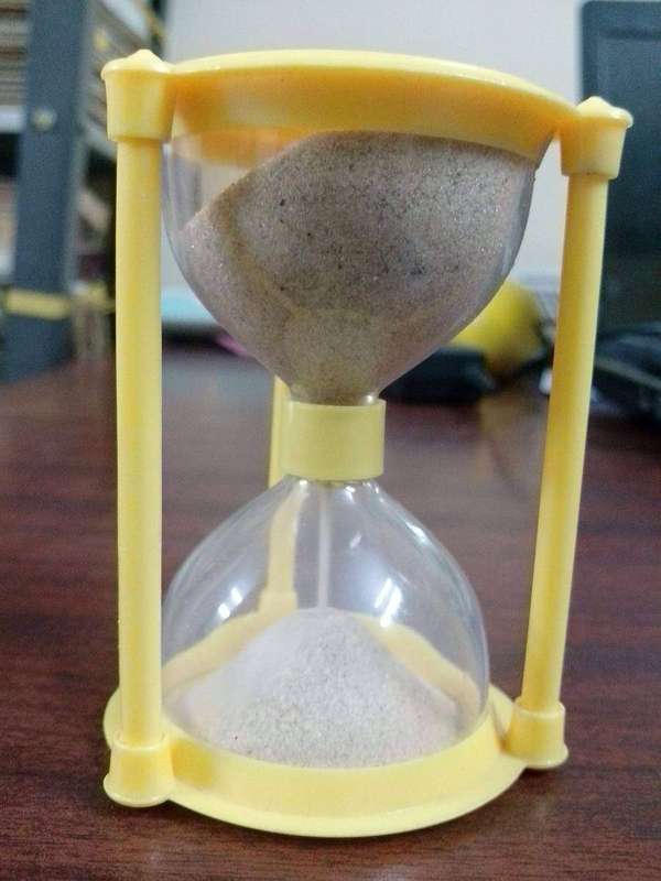 A sand clock photographed up close, its grains marking time as it passes