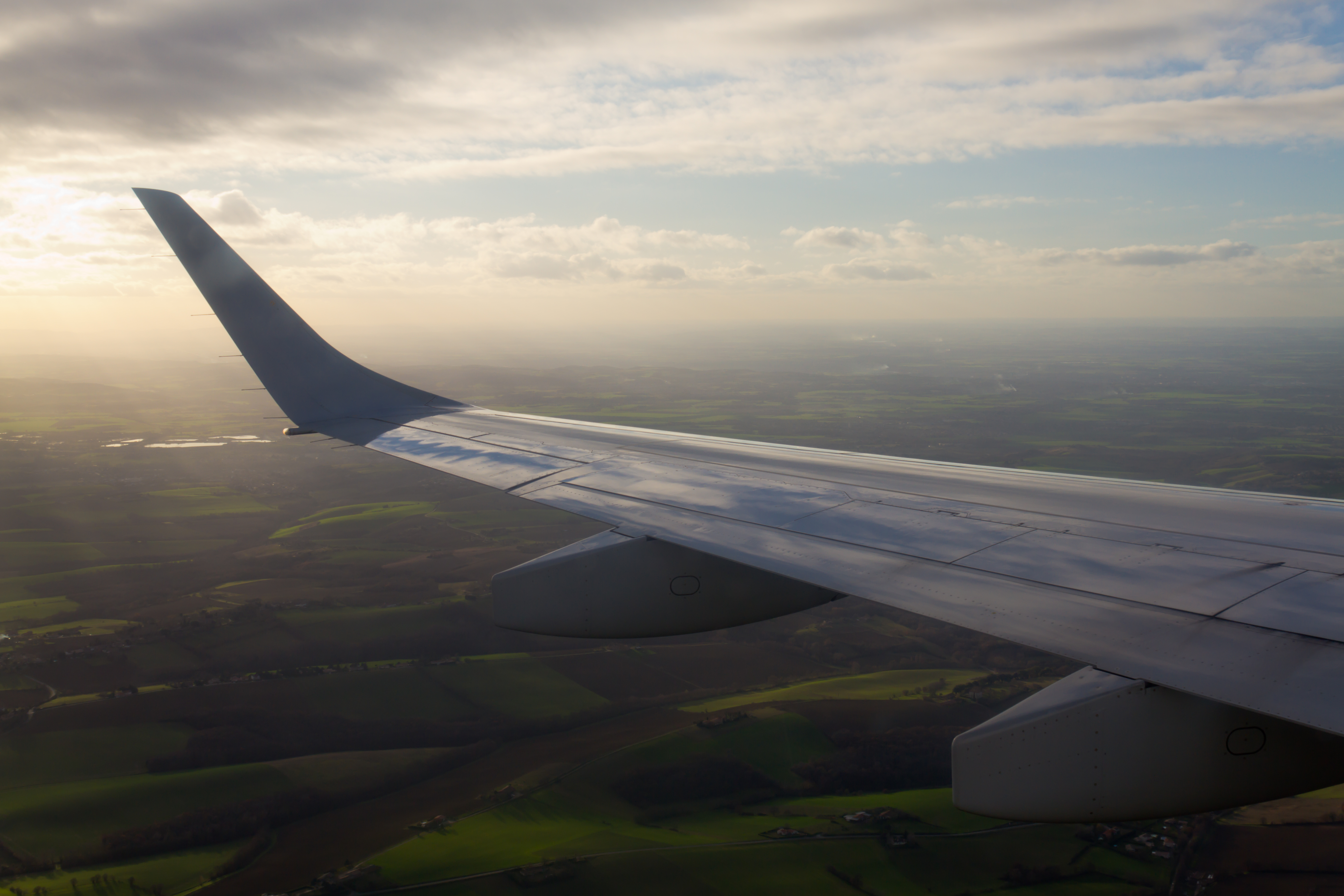 Airplane wing and winglet glowing at sunset above the clouds