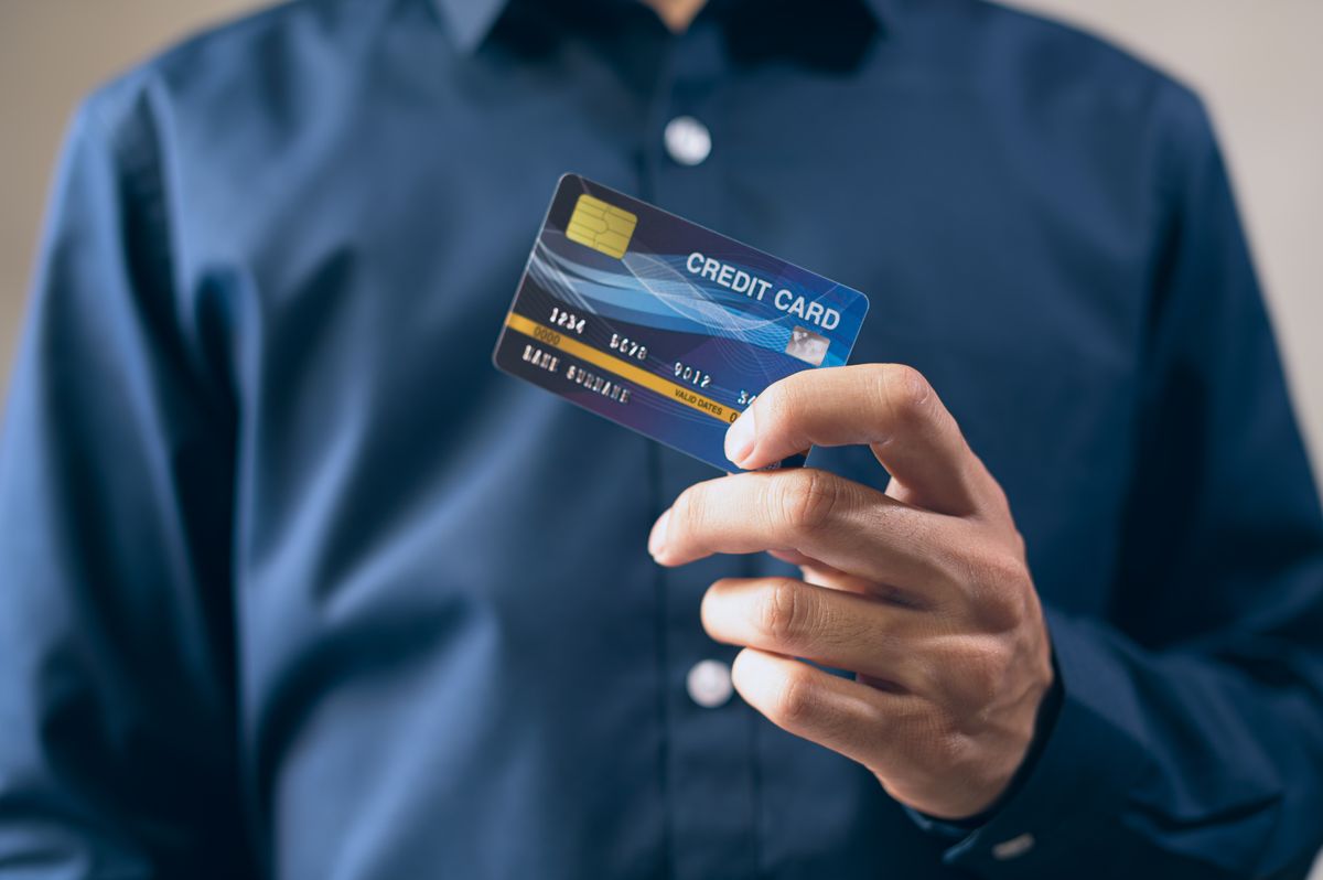 A hand holding a credit card, representing the debt moved by a balance transfer