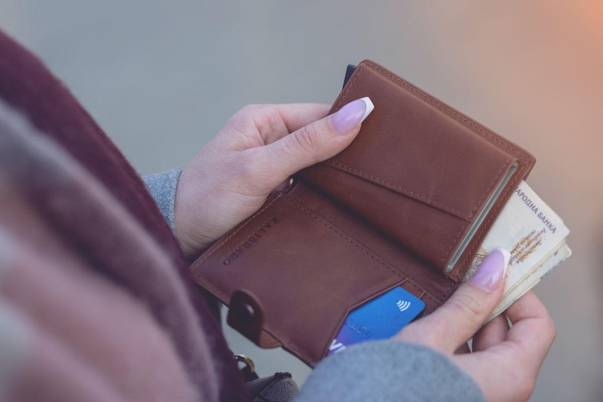 A wallet holding banknotes and a credit card, the everyday context of card debt