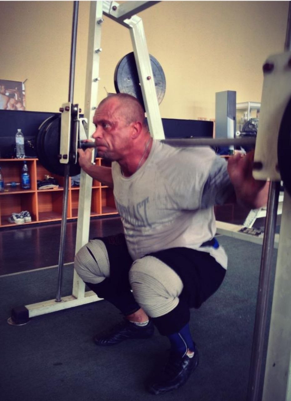 A lifter performs a barbell squat in a gym