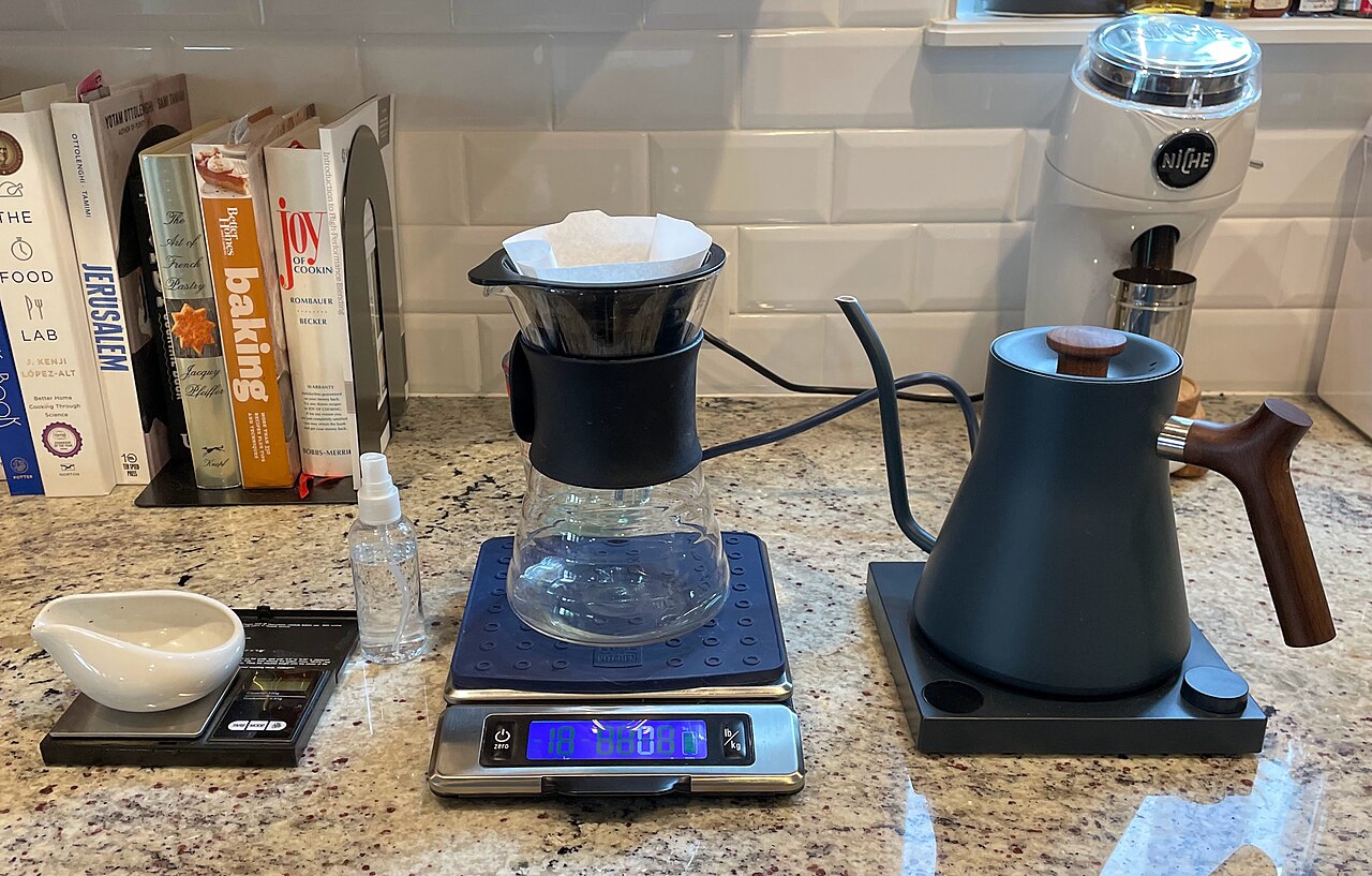 Pour-over coffee brewing setup with dripper, kettle, and glass carafe