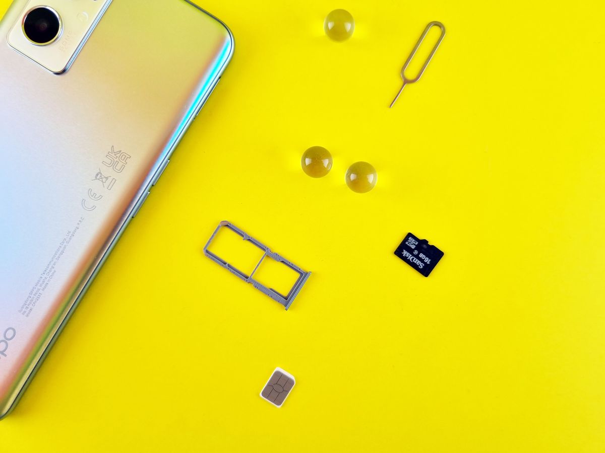 A smartphone next to a SIM card and SIM tray on a bright surface