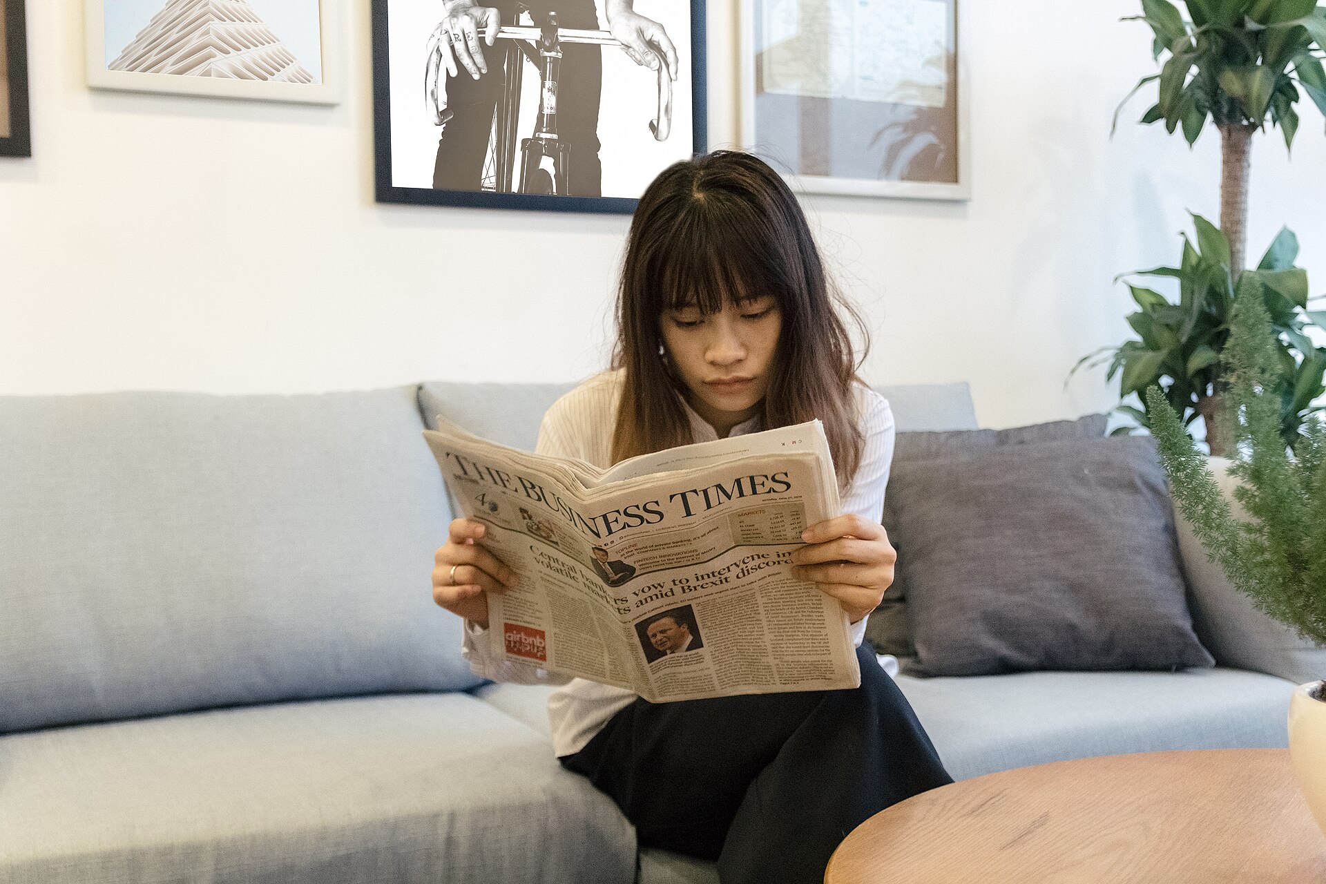 A person reading a newspaper at a table