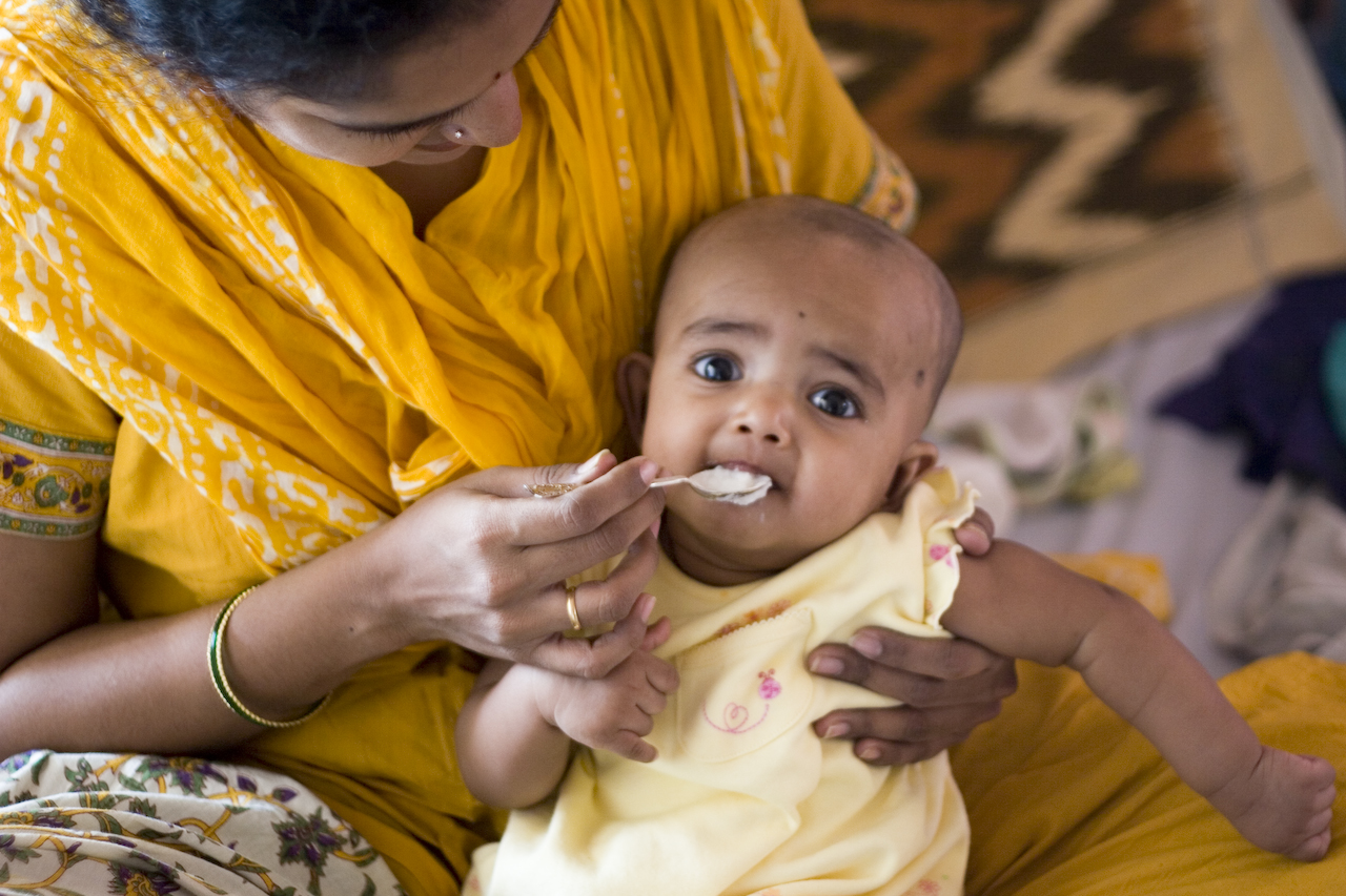 Mother spoon-feeding an infant a spoonful of rice cereal