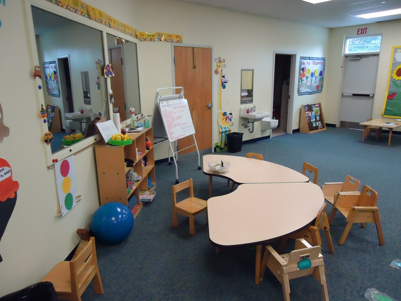 An empty preschool classroom with small tables and chairs