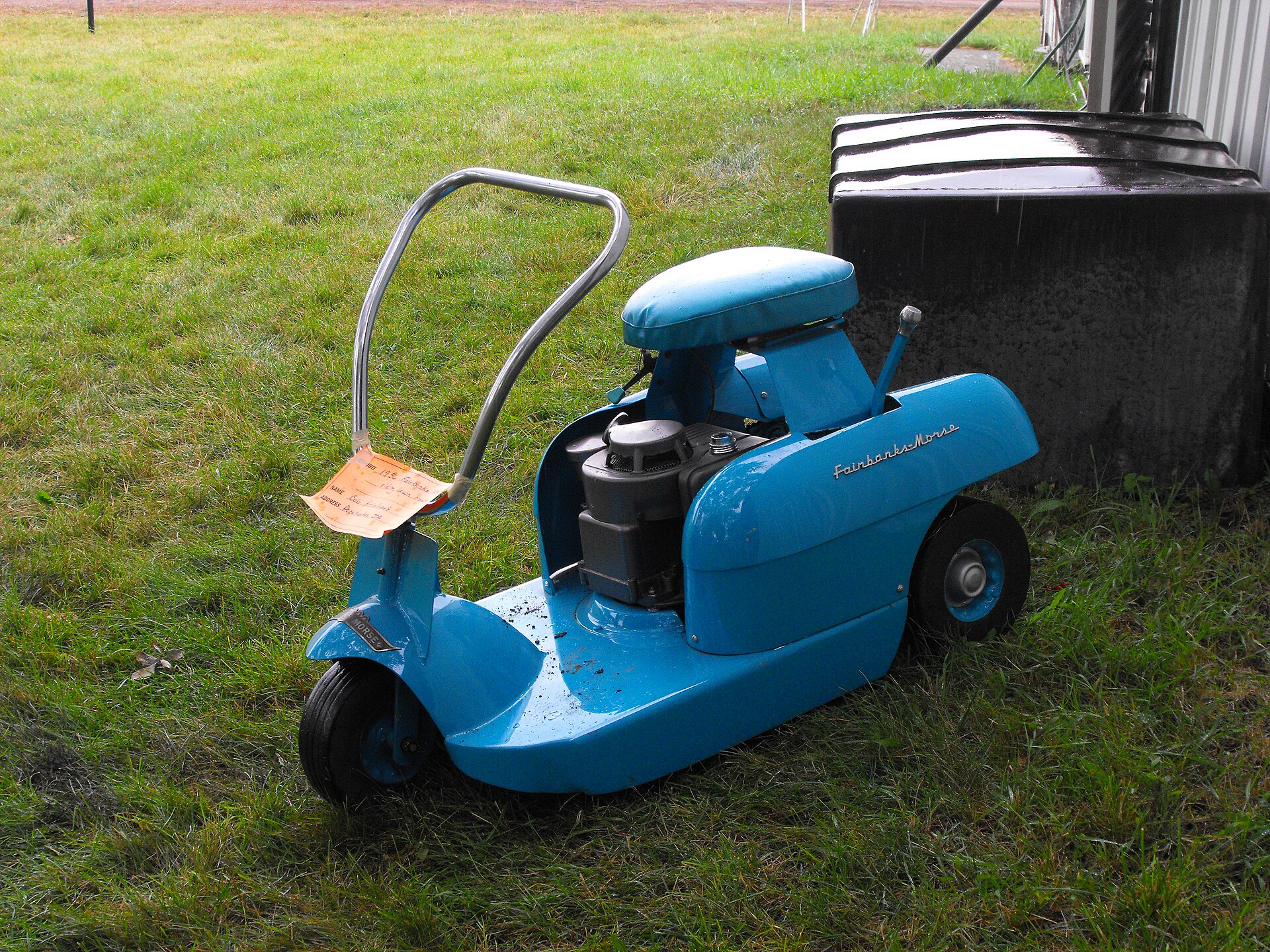 A vintage blue ride-on lawn mower parked on green grass