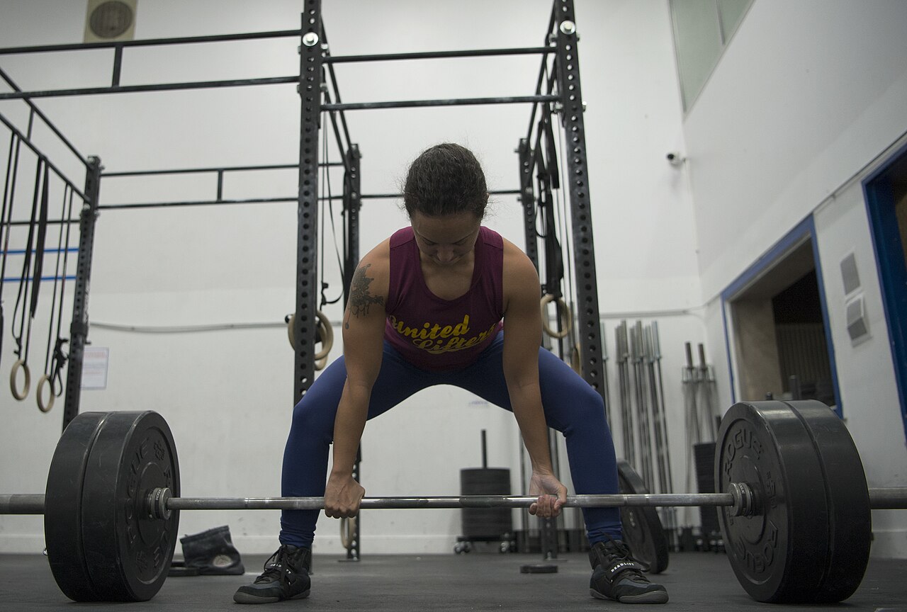 Woman performing a deadlift with a loaded barbell in a gym