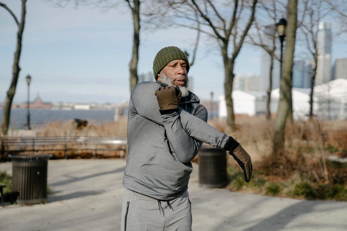 An older man exercising outdoors in the morning, part of a cramp-prevention routine
