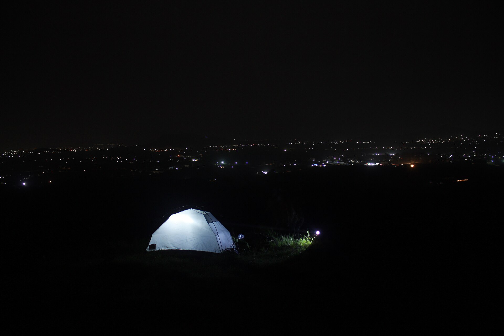 A tent pitched at a night campsite under the sky