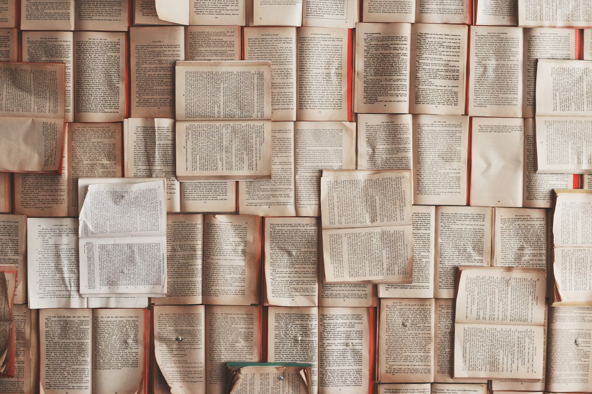 A stack of open books on a desk used for essay research