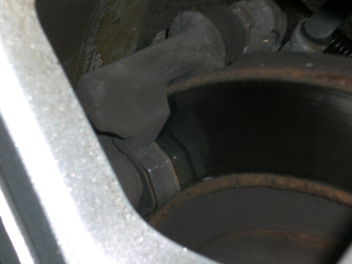 Brake caliper and pad visible through a car wheel