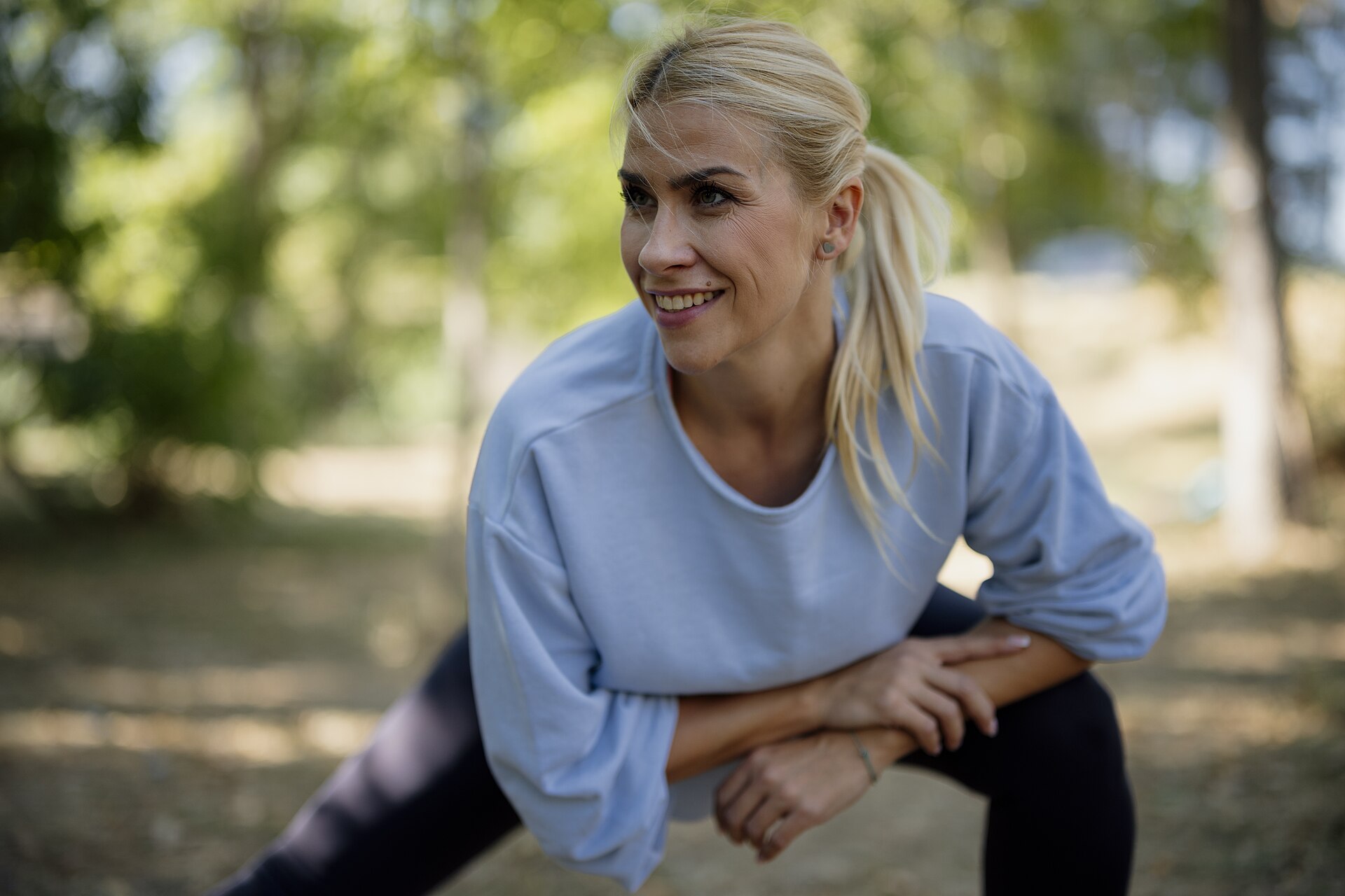 A woman stretching outdoors in a park on a sunny day