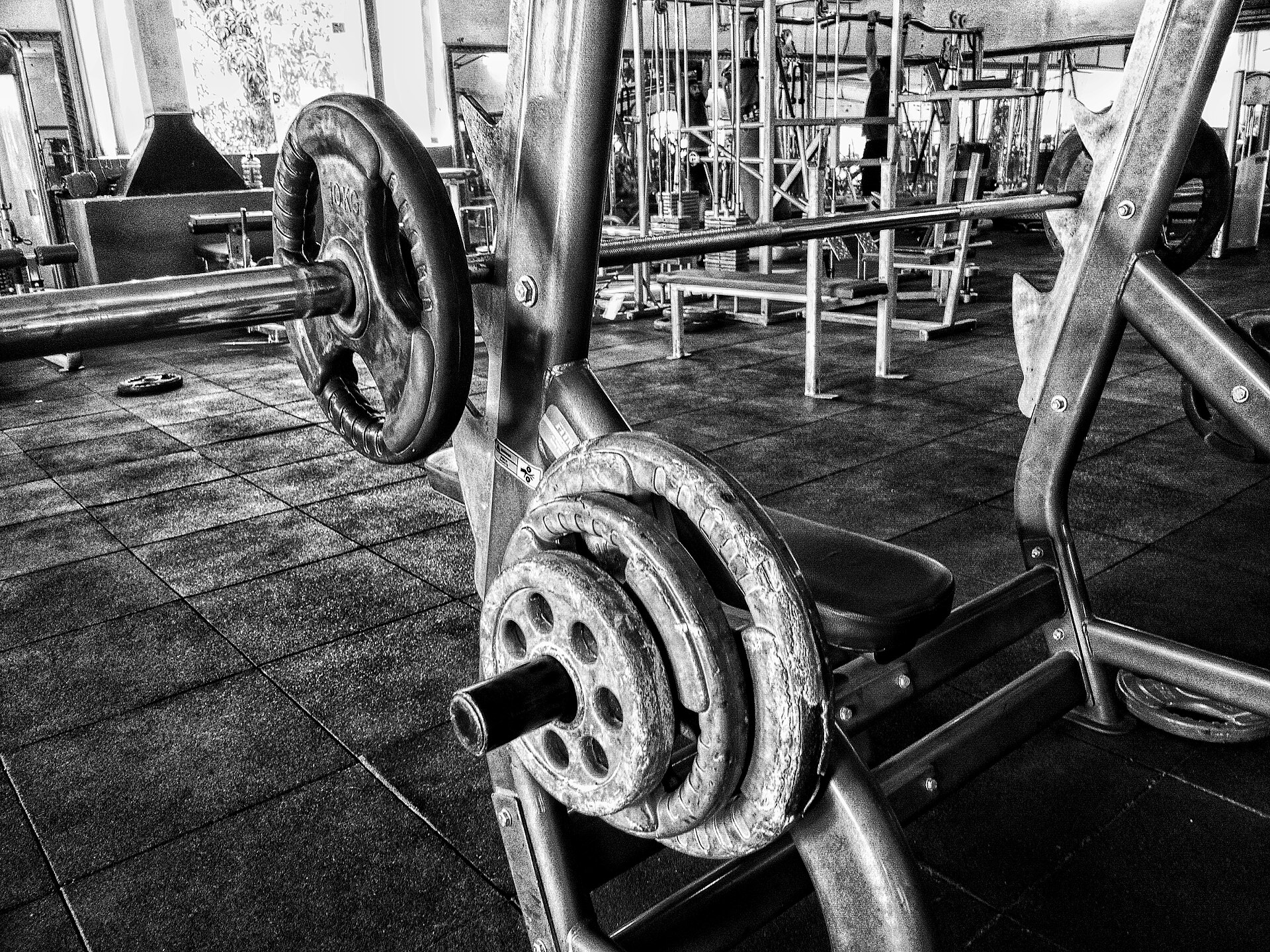 A person performing a barbell bench press in a gym