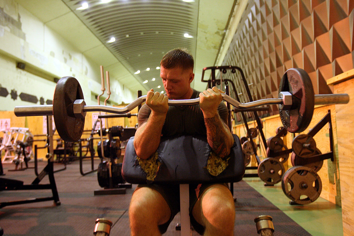 A Marine working out with weights in a gym