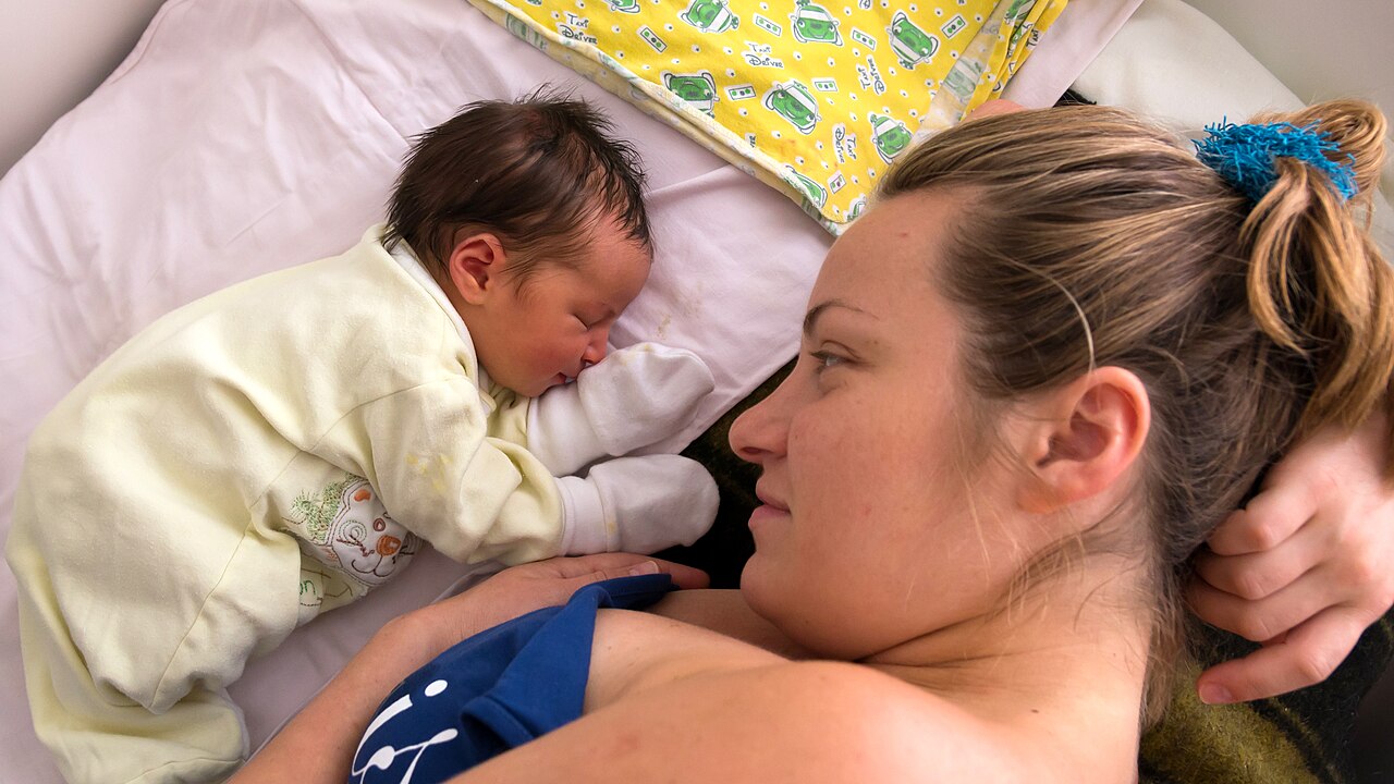 A mother holding her newborn daughter, the bond the older child is learning to share