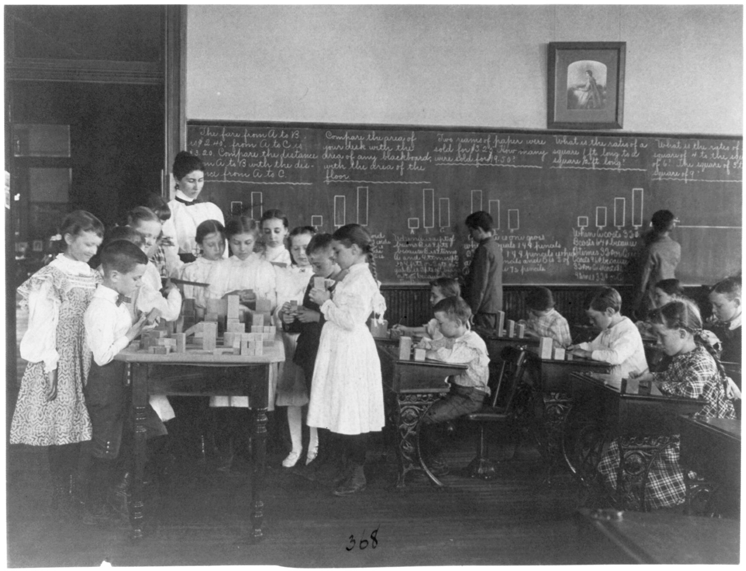 A historic photograph of students at a blackboard during a mathematics class.