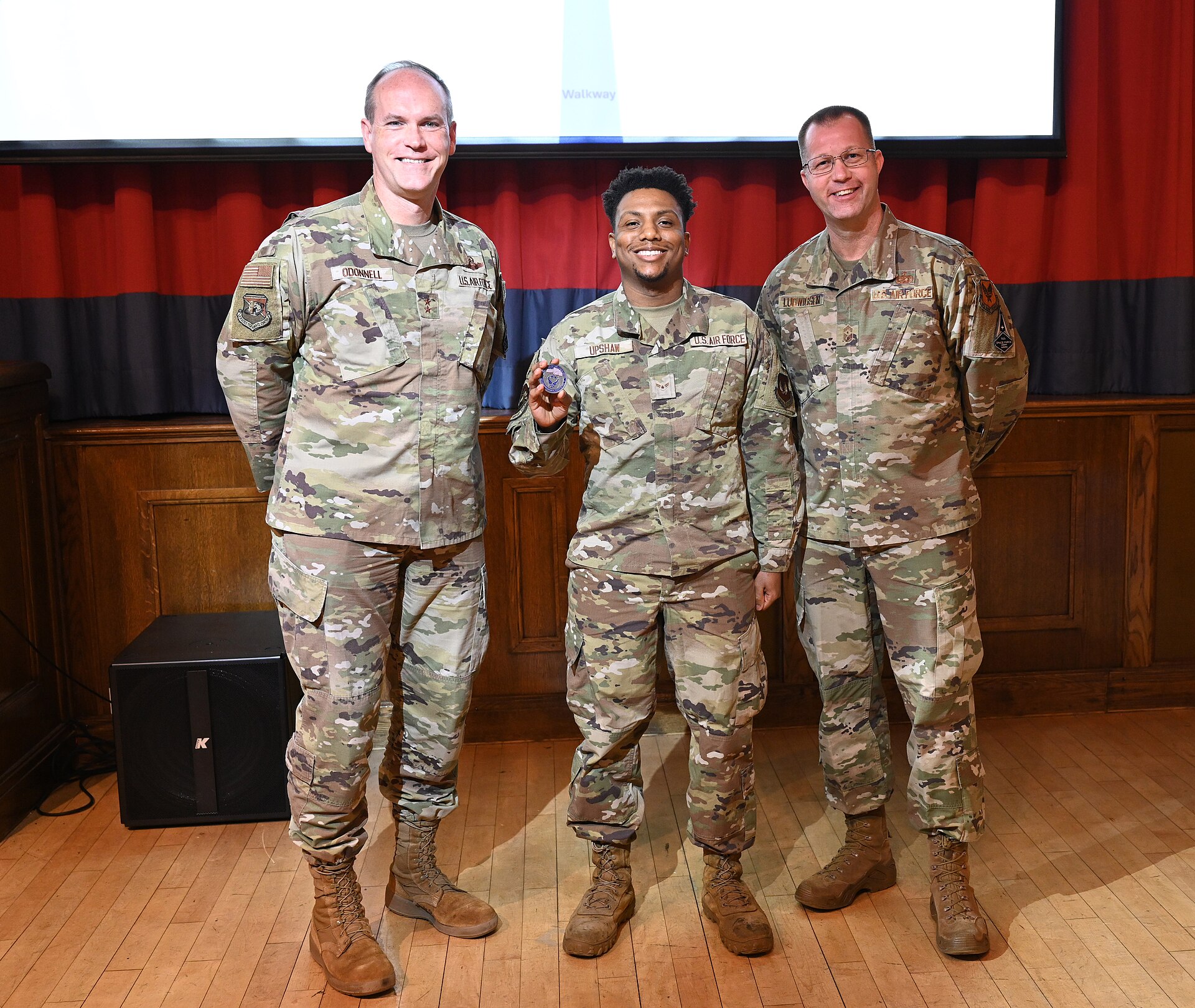 Three U.S. Air Force service members posing at an awards ceremony