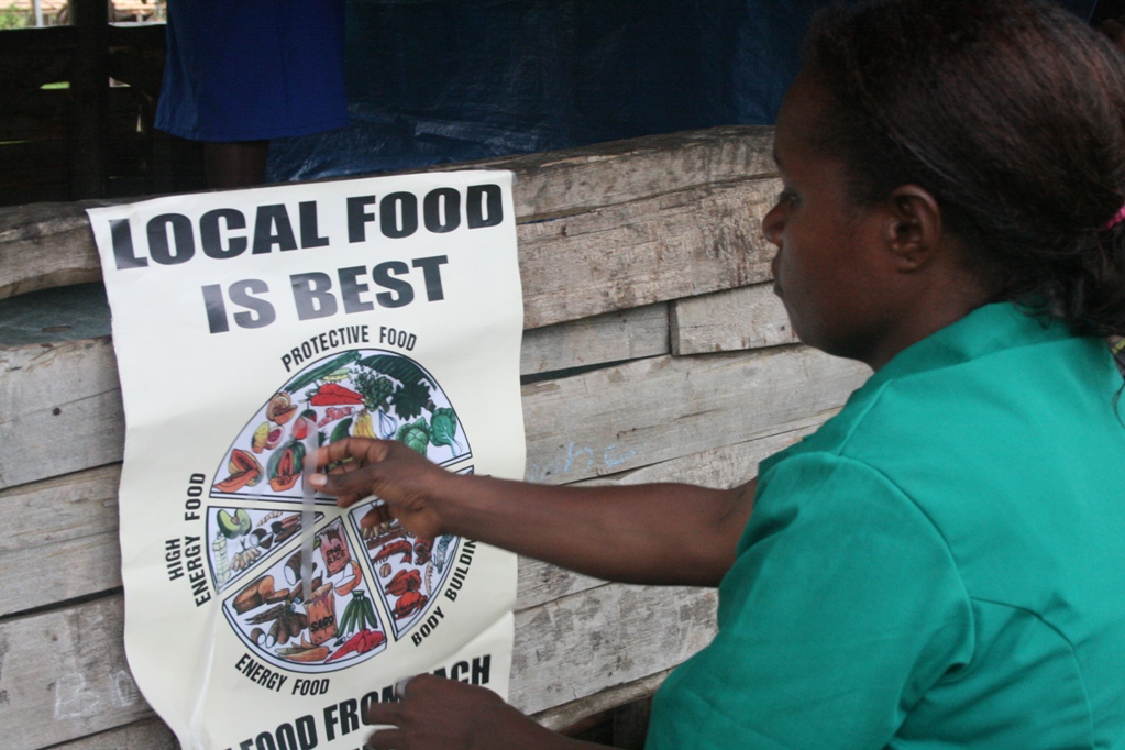 A nurse putting up a health-education poster in a village