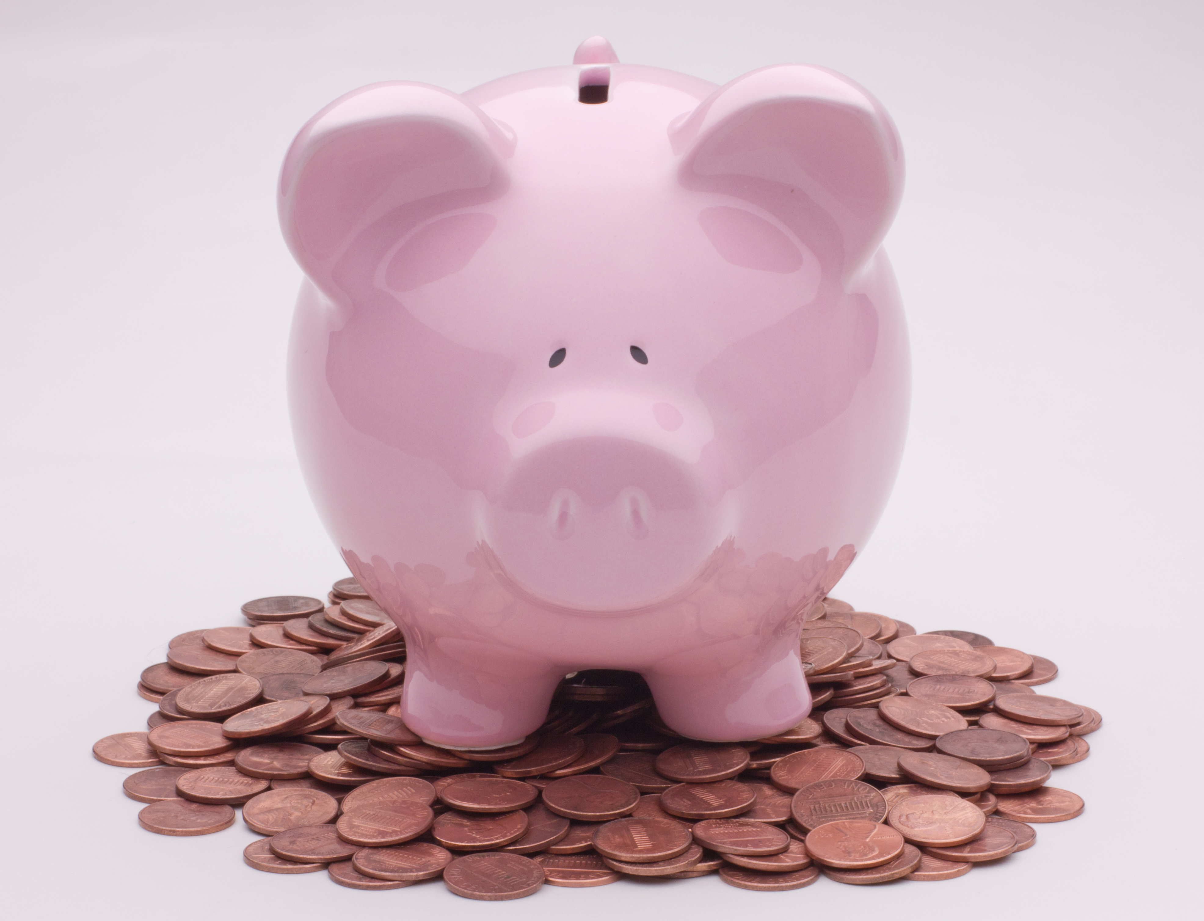 A piggy bank standing on a spread of pennies, symbolizing small regular contributions adding up over time