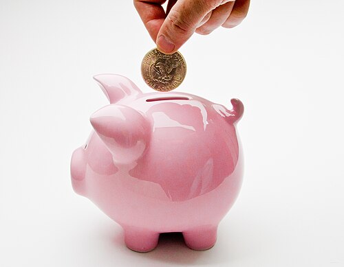 A hand dropping a coin into a piggy bank, illustrating the basic idea of contributions triggering employer additions