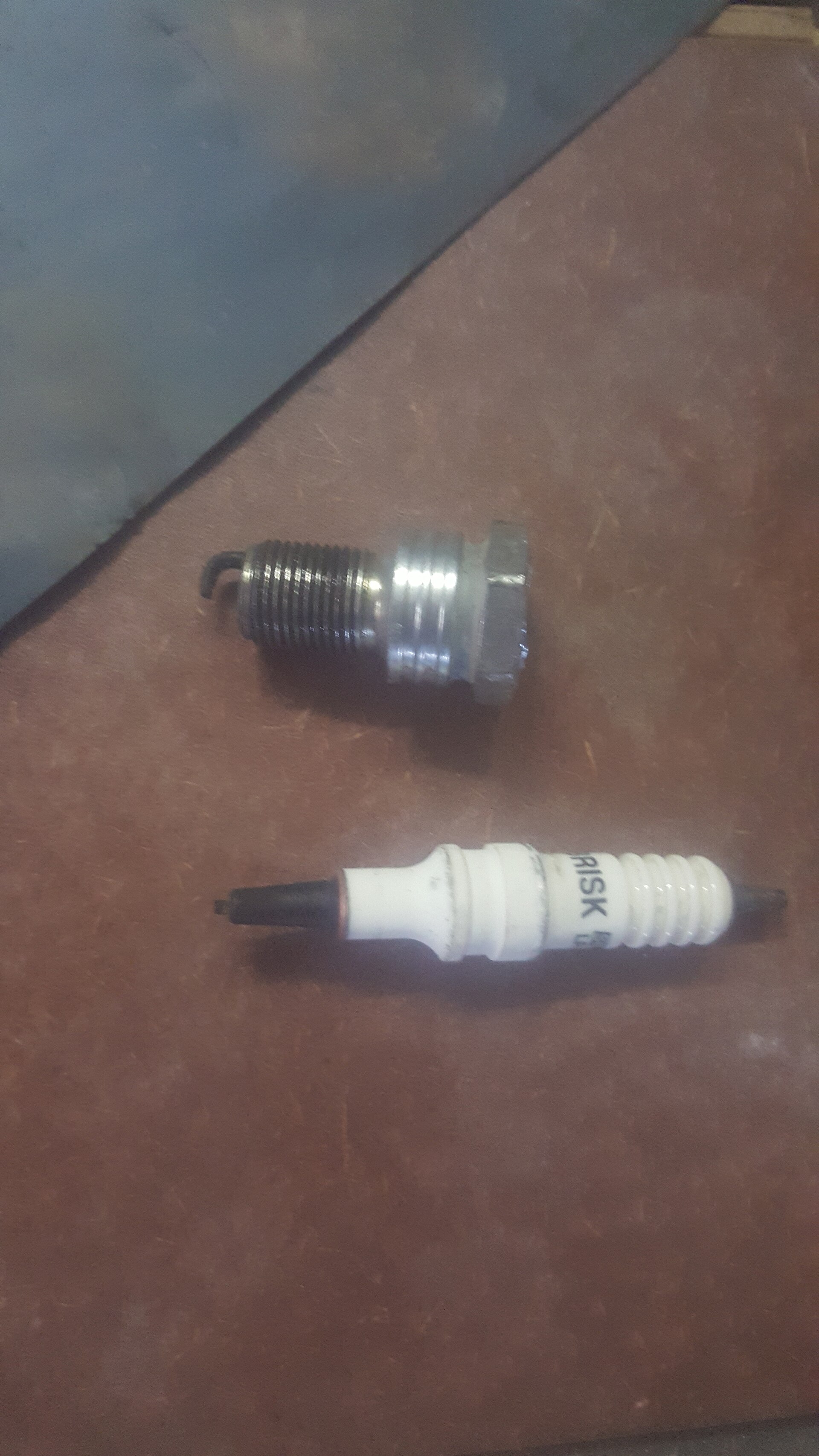 A broken spark plug lying next to an intact one