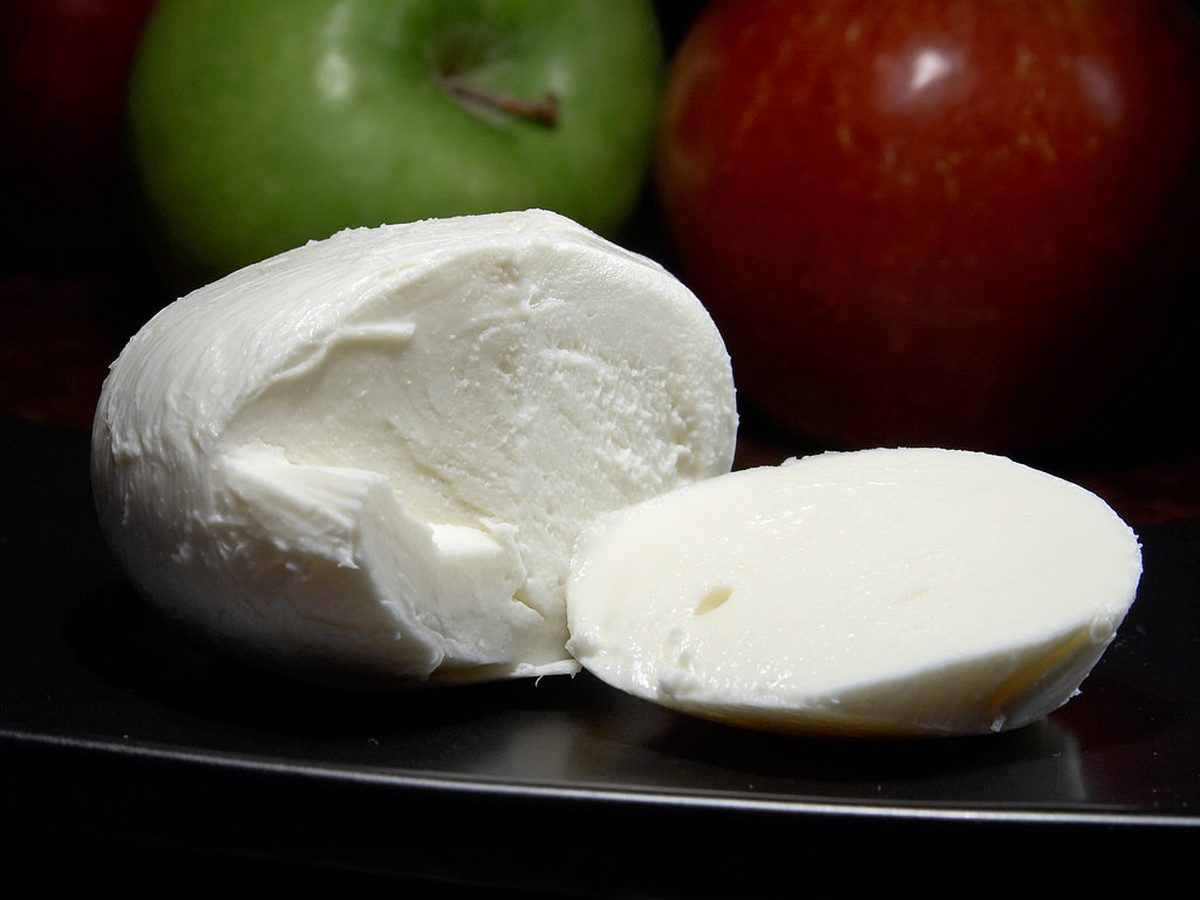 A ball of fresh mozzarella, one half sliced