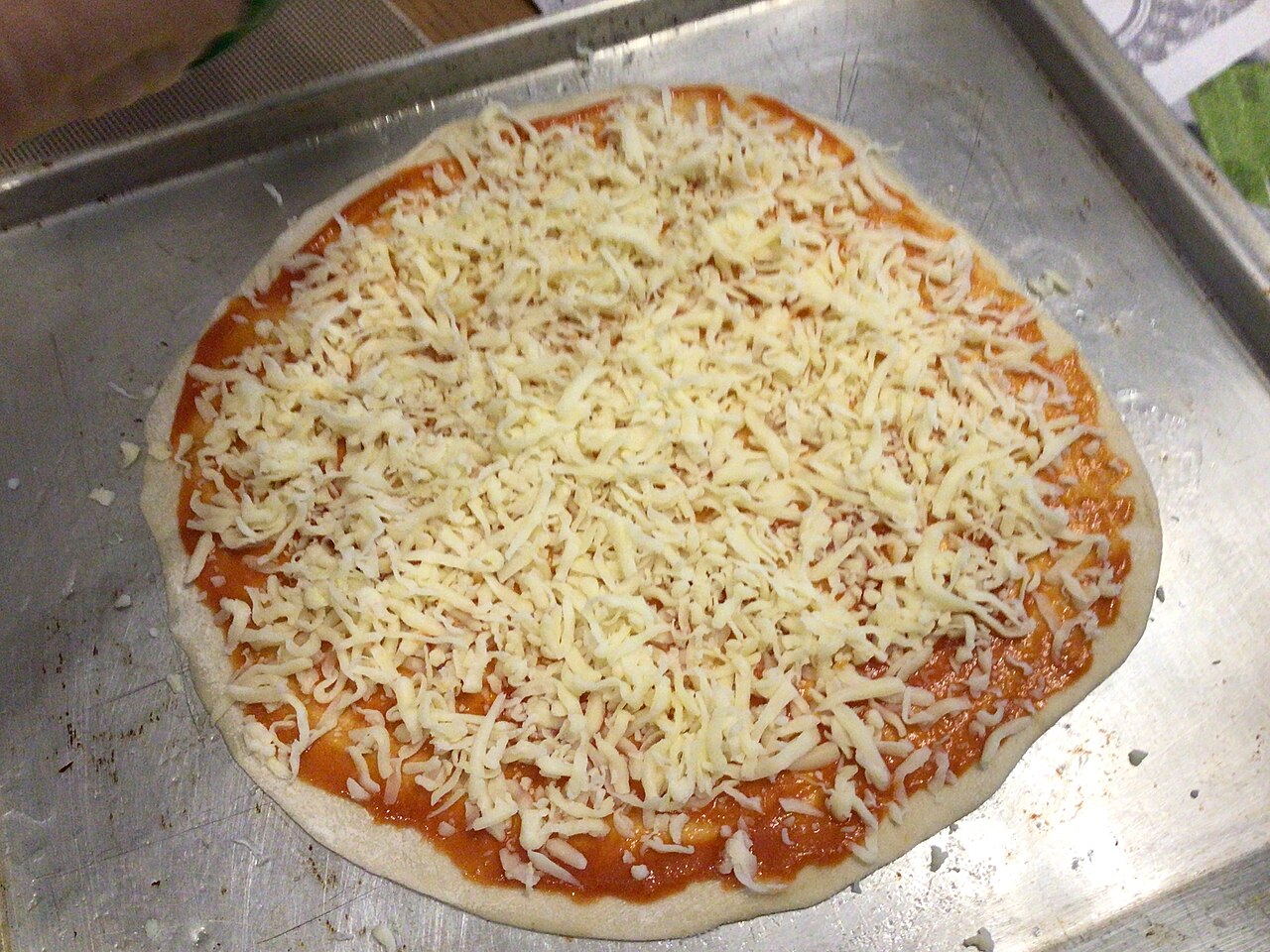 An uncooked homemade cheese pizza