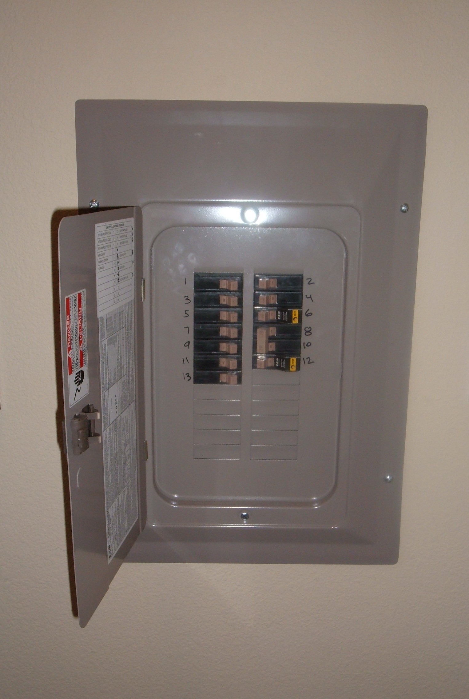 An open residential circuit breaker panel with rows of breakers