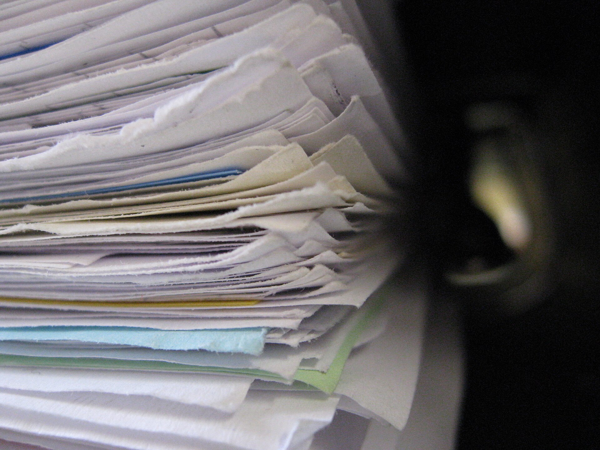 A tall stack of documents and files, representing the credit reports that inquiries leave their marks on