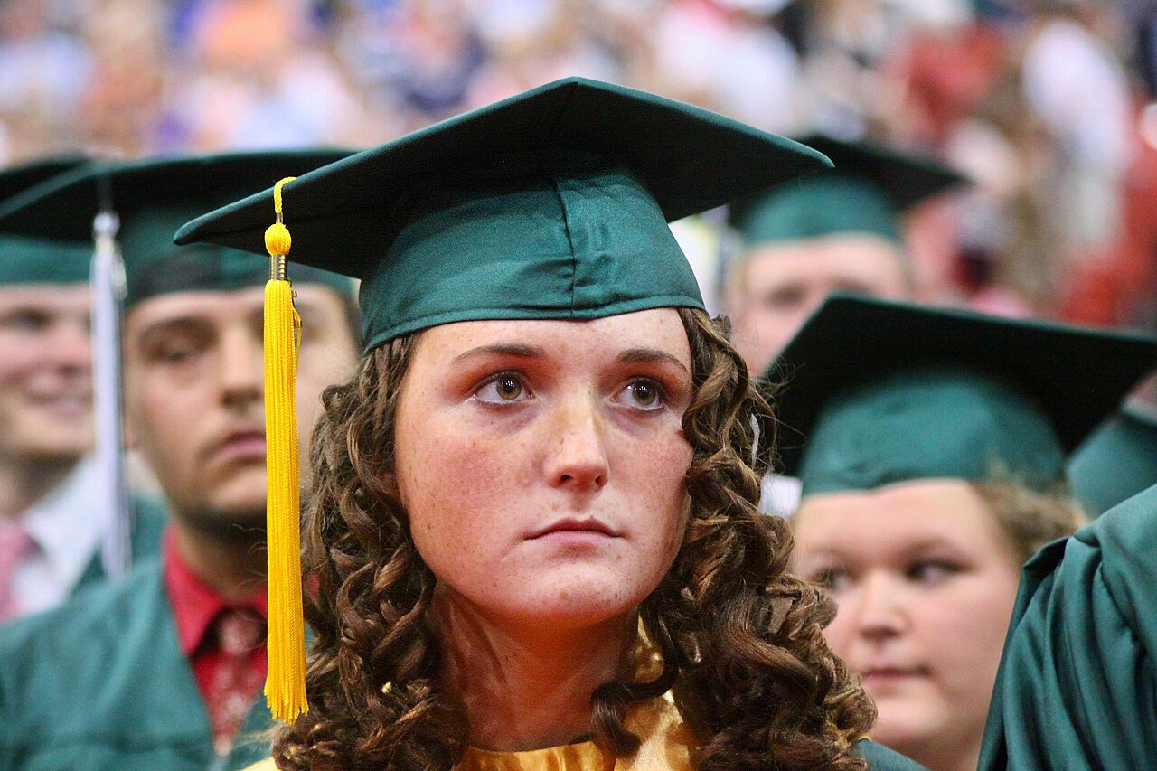 A high school graduate in cap and gown at a graduation ceremony