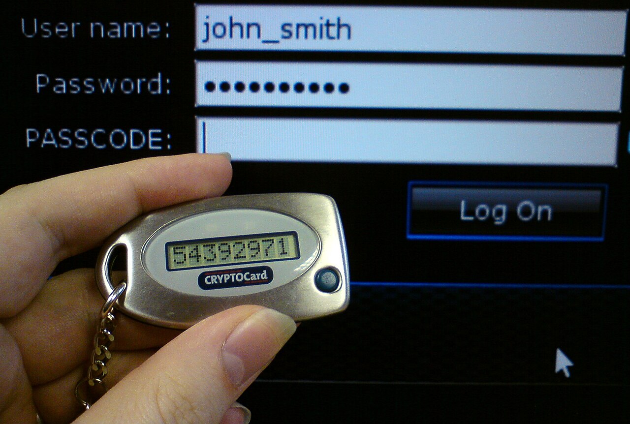 A CryptoCard hardware token held in front of a login screen with a passcode field