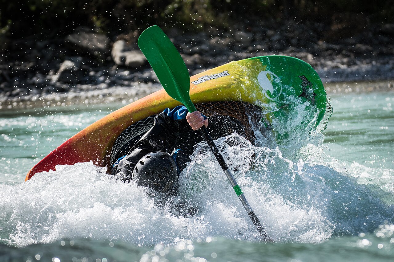 A kayaker playboating on a river