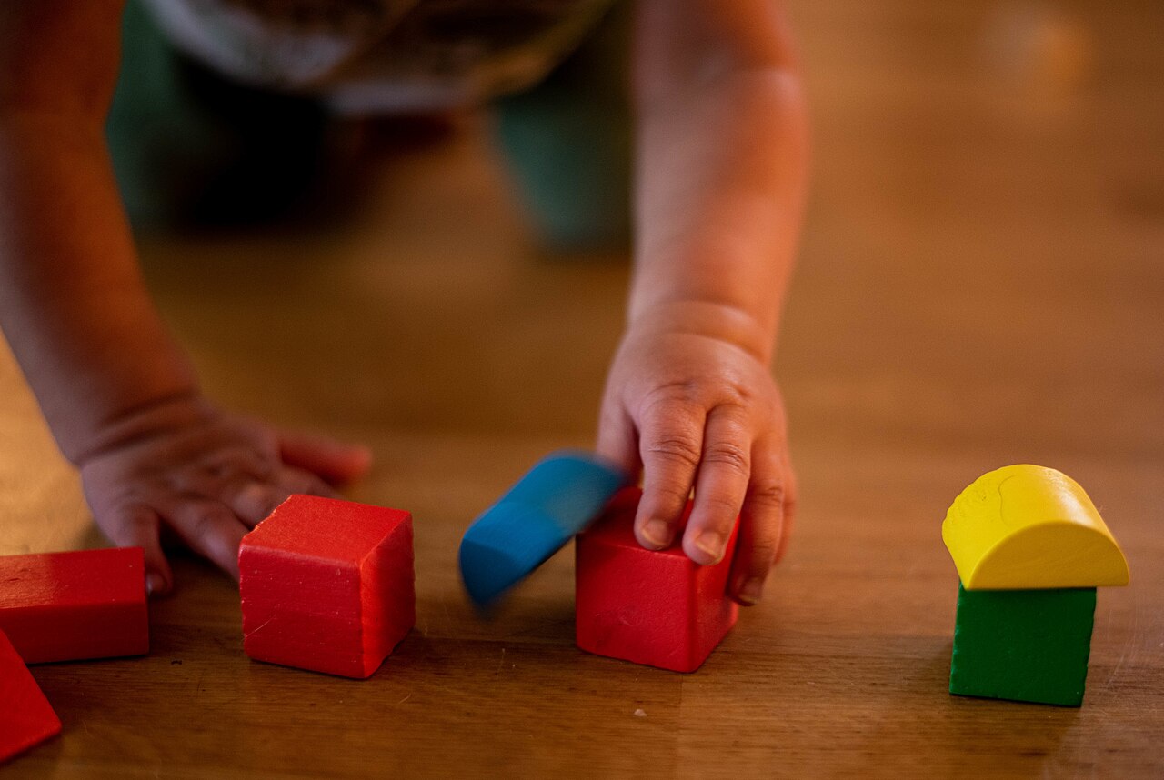 A toddler's hands stacking colorful blocks