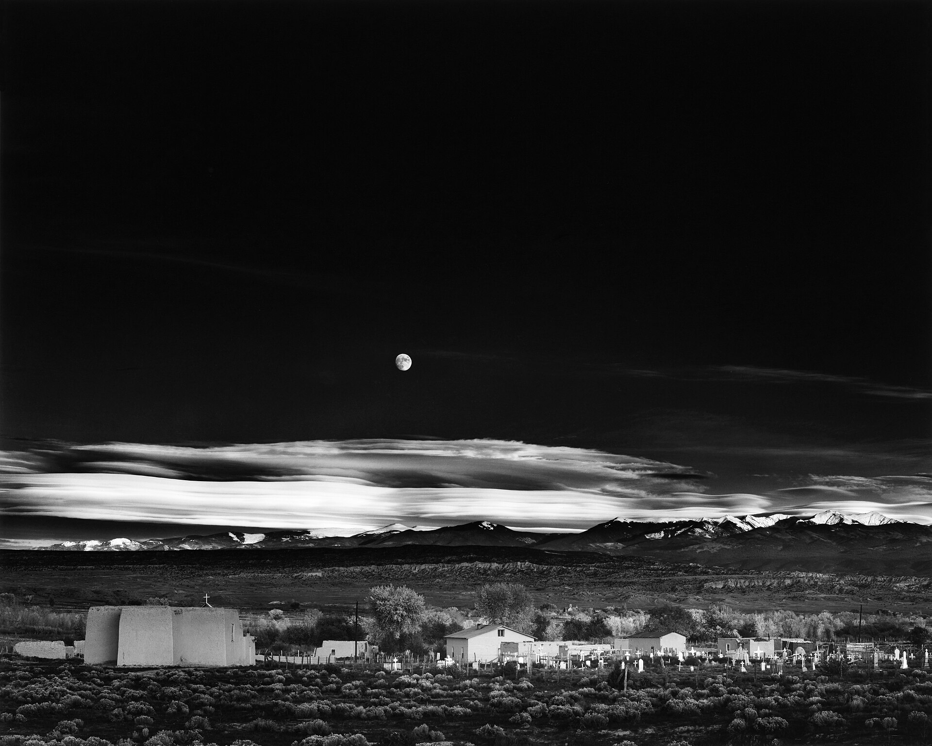 A large full moon rising over a town on the horizon